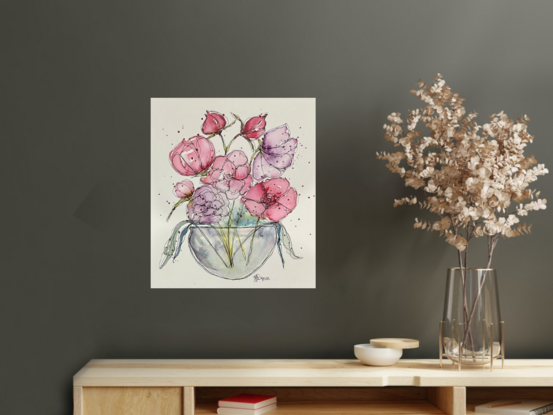 A bouquet of soft pastel flowers in pink and mauve in a round glass vase