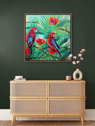 his painting depicts two vibrant rosella parrots perched among lush green foliage and bright red flowers. The birds, predominantly red with blue accents on their wings and tails, are positioned in a lively tropical setting.