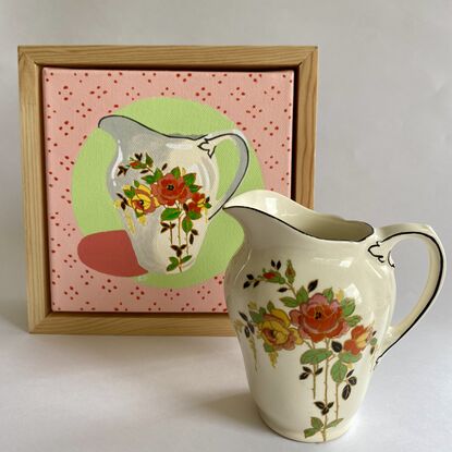 Small china jug  with floral pattern set on a green and pink background 