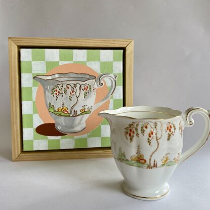 White ceramic jug with orange blossom tree decoration set on a green and white check background 