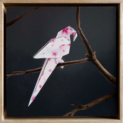 An origami parrot, with a cherry blossom pattern, perched on a bare branch. 