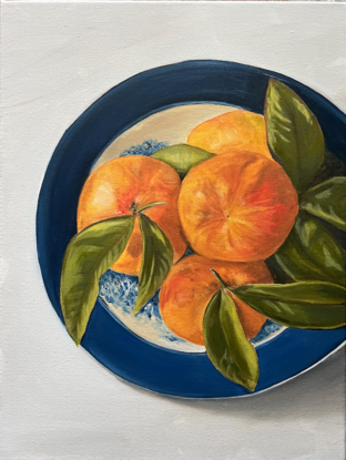 Juicy orange mandarins with green leaves on blue and white plate