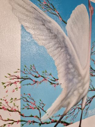 A painting of a white crane in mid-flight with wings outstretched, set against a vibrant blue background. The bird is surrounded by branches adorned with delicate pink blossoms, creating a serene and elegant composition.