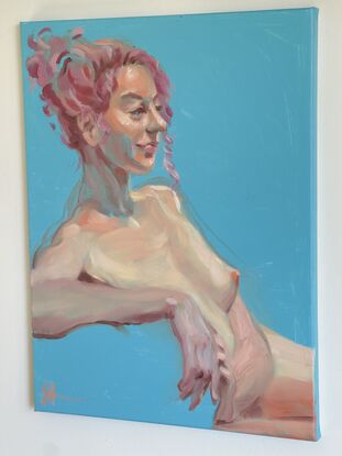 This painting depicts a nude woman with pink hair against a bright blue background. The subject is rendered in soft, fluid brushstrokes, highlighting her relaxed pose and serene expression. Light and shadow play across her form, emphasizing the natural beauty and grace of the human body.