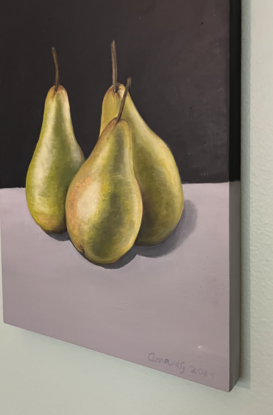 Three green pears on a bench top 