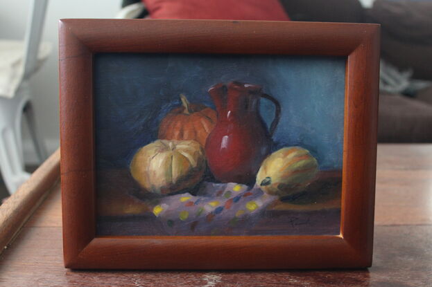 Pumpkins and red vase on a table with a colourful tablecloth.