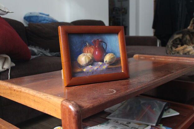 Pumpkins and red vase on a table with a colourful tablecloth.