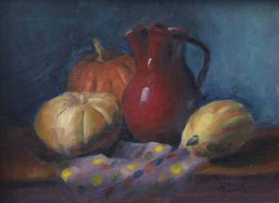 Pumpkins and red vase on a table with a colourful tablecloth.