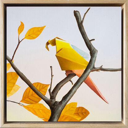 A purple and pink origami parrot perched on a bare branch with purple flowers growing. 