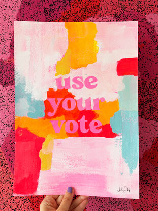 abstract acrylic painting with vibrant colours with the text "use your vote" front and centre, in pink.