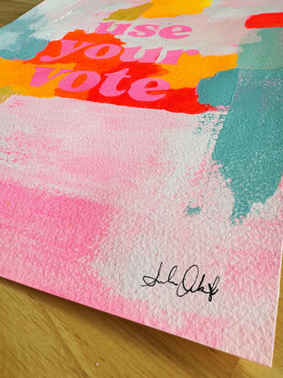 abstract acrylic painting with vibrant colours with the text "use your vote" front and centre, in pink.