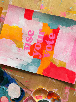 abstract acrylic painting with vibrant colours with the text "use your vote" front and centre, in pink.