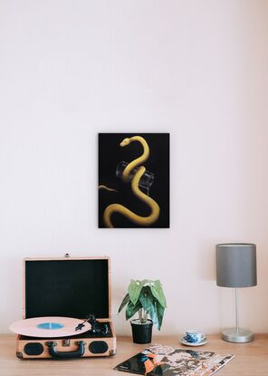 A small yellow snake on a black background, holding a glass.