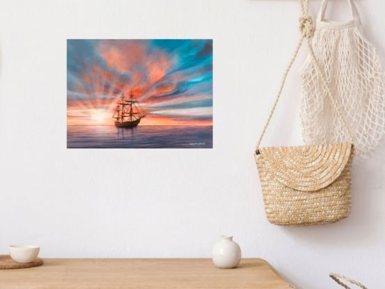 A n electric moment of  beautiful oldFrigate tall ship silhouetted by a dramatic sunset  of reds and oranges with hues of purple soft clouds running through bursting sun rays with a calm glassy ocean in foreground full of purple and blue hues 