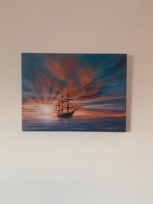 A n electric moment of  beautiful oldFrigate tall ship silhouetted by a dramatic sunset  of reds and oranges with hues of purple soft clouds running through bursting sun rays with a calm glassy ocean in foreground full of purple and blue hues 