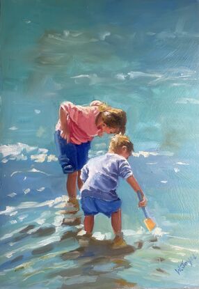 A young boy and girl bend over looking for fish in the shallow water at the edge of the ocean