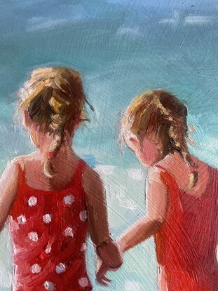 Two young girls in bright red bathers walk into a sparkling ocean