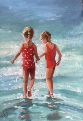 Two young girls in bright red bathers walk into a sparkling ocean