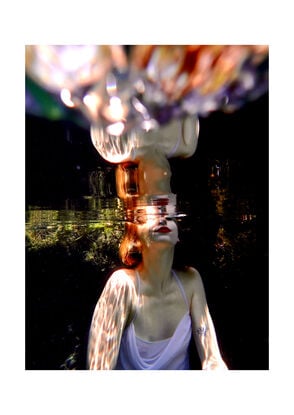 A woman in water with her upper face and head breaking the water's surface creating a mirror-like reflection.