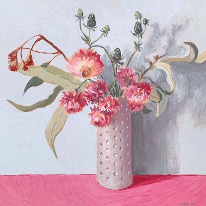 Pink daisy flowers and gum bouquet in white vase on pink background