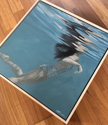 A woman in black and white striped swimwear, swimming in blue-green water with light reflections, ripples, bubbles and water droplets.