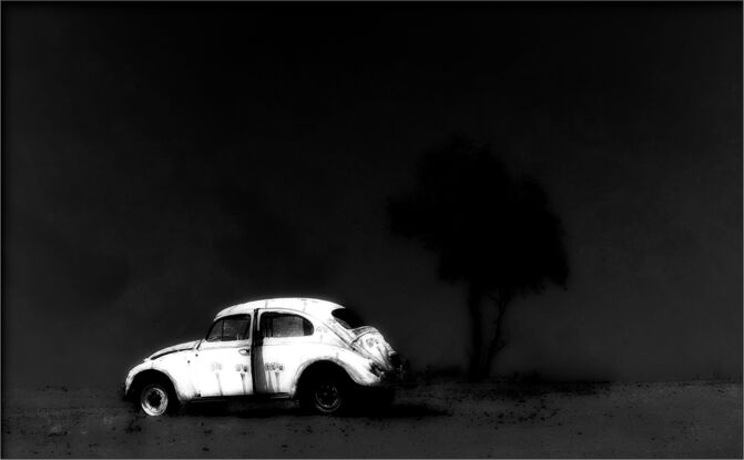 A black and white photograph of a Volkswagen Beetle.