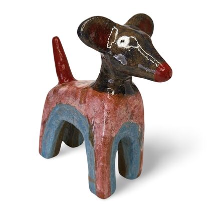 This stoneware sculpture features a stylised puppy distinguished by its vibrant, multi-colored glaze and  large ears and a pronounced snout. The colour and simple form highlight the fun nature of the piece.