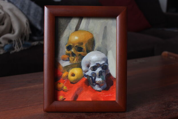 Original oil painting of two skulls and fruit on an orange tablecloth