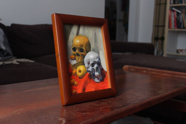 Original oil painting of two skulls and fruit on an orange tablecloth