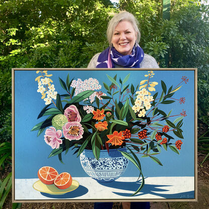 A still life painting of flowers and fruit in blues, reds, oranges, yellows, whites, pinks and greens, framed in oak