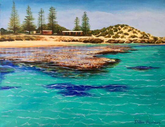 The Basin swimming area at Rottnest Island, with the sheds and pine trees in the background. The foreground features the reef surrounding the island, a favourite swimming and snorkeling spot for holidaymakers. The reef in the foreground is highlighted by the surrounding turquoise waters.