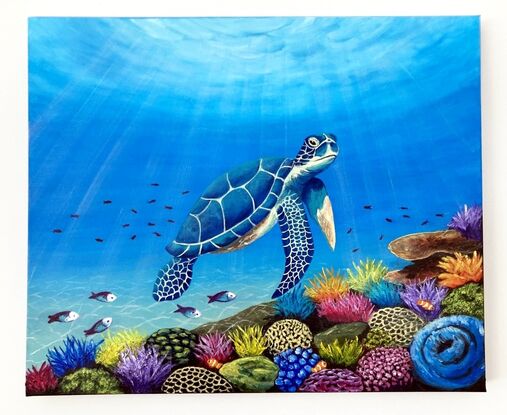 A blue green sea turtle swimming over a multi-coloured coral reef with sunlight shining down through the water. The coral is yellow, blue, purple and pink coloured with green and pink parrot fish and clown fish and other small tropical fish swimming over the reef.