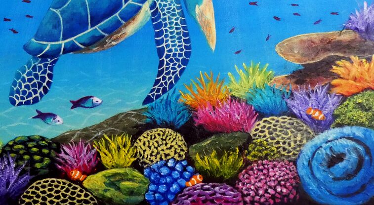 A blue green sea turtle swimming over a multi-coloured coral reef with sunlight shining down through the water. The coral is yellow, blue, purple and pink coloured with green and pink parrot fish and clown fish and other small tropical fish swimming over the reef.