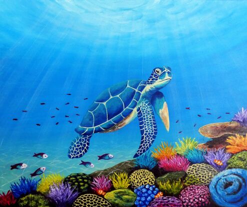 A blue green sea turtle swimming over a multi-coloured coral reef with sunlight shining down through the water. The coral is yellow, blue, purple and pink coloured with green and pink parrot fish and clown fish and other small tropical fish swimming over the reef.