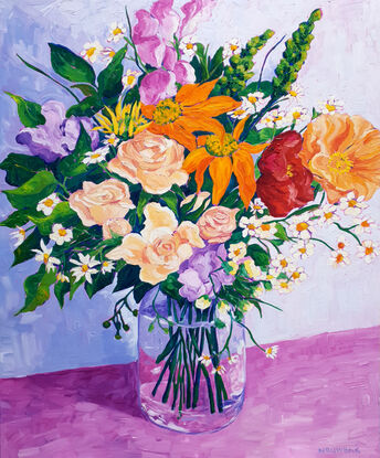 Mixed bunch of colourful flowers in a glass vase on a table.