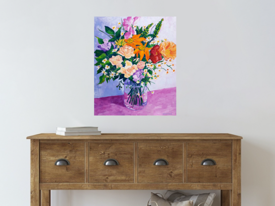 Mixed bunch of colourful flowers in a glass vase on a table.