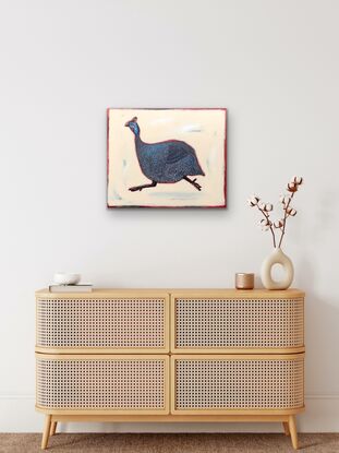 Guinea fowl running on a beige abstract backgroun, red and brown edges.