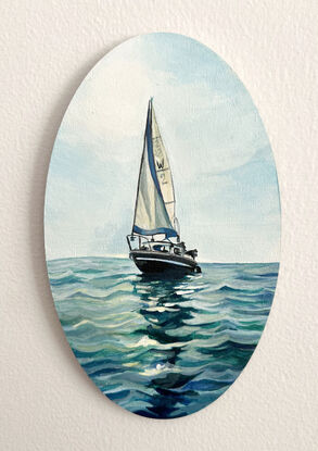 Classic white and black yacht sails in the centre of a seascape with shimmering reflections on the water.
