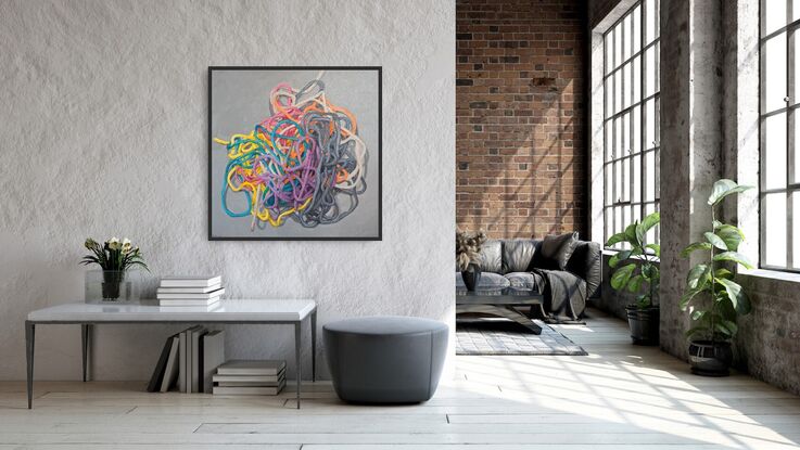 A birds eye view of a colourful pile of woollen threads on a grey background.