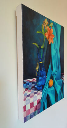 Orange lily in blue vase and an orange mandarin trying to hide in a silky turquoise blue fabric