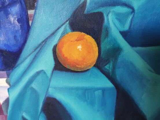 Orange lily in blue vase and an orange mandarin trying to hide in a silky turquoise blue fabric