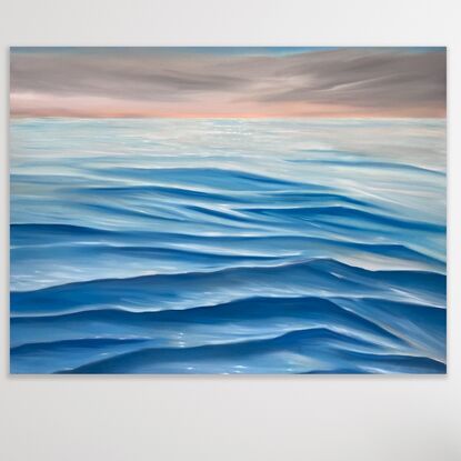 Ocean surface with ripples and lights under a peach and grey sky 