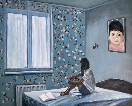 A girl sits on a bed hugging her knees beside a window  in a room decorated with floral wallpaper and a large portrait of a young child. At her feet are the open pages of a blank book.