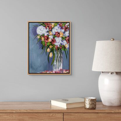 A bouquet of flowers in a tall glass Vase,  A blue grey wall with soft shadows.