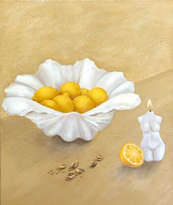 A clam shell holding juicy lemons sits behind scattered pistachios and a lit candle in the shape of a woman on a textured beige yellow background.