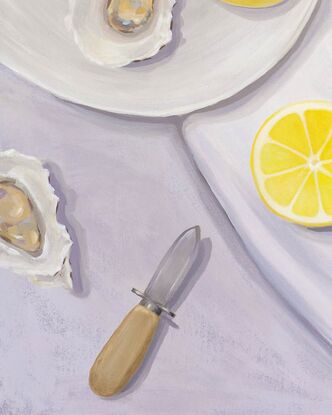 A tabletop view from above showing juicy lemons, oysters, a bowl of salt, and oyster shucker & a seashell.