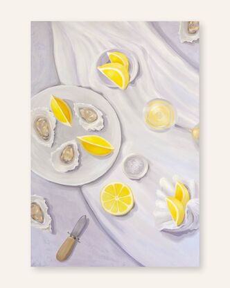 A tabletop view from above showing juicy lemons, oysters, a bowl of salt, and oyster shucker & a seashell.