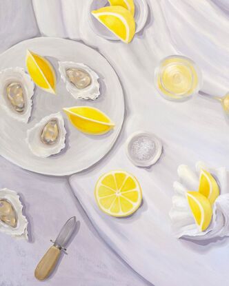 A tabletop view from above showing juicy lemons, oysters, a bowl of salt, and oyster shucker & a seashell.