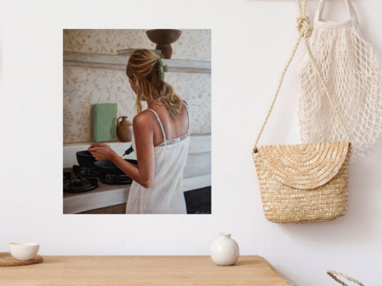 Young lady with her back to the camera, wearing a white linen dress and cooking in a kitchen