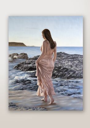 A lady, with her back towards the camera, walking on the beach